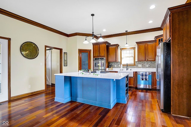 kitchen with pendant lighting, tasteful backsplash, a center island, stainless steel appliances, and dark wood-type flooring