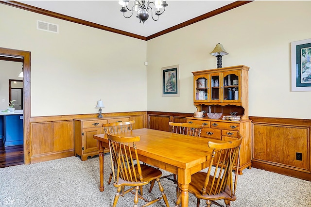 carpeted dining area with an inviting chandelier, ornamental molding, and wooden walls