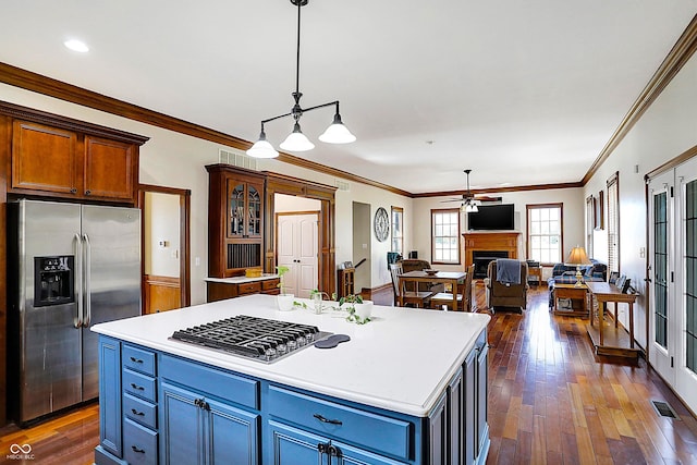 kitchen featuring crown molding, ceiling fan, hanging light fixtures, stainless steel appliances, and a center island