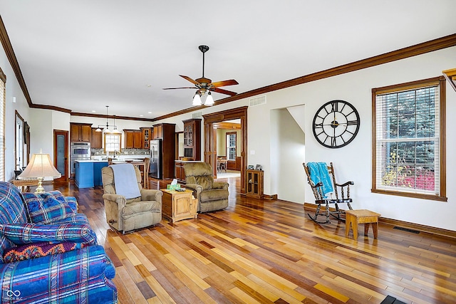 living room featuring ornamental molding, a healthy amount of sunlight, hardwood / wood-style floors, and ceiling fan