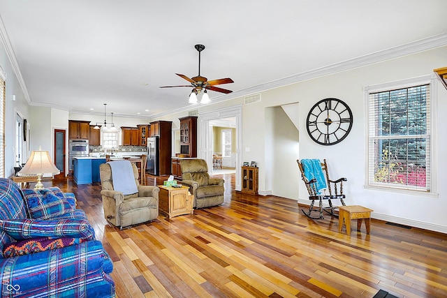 living room with dark wood-type flooring, ornamental molding, and ceiling fan