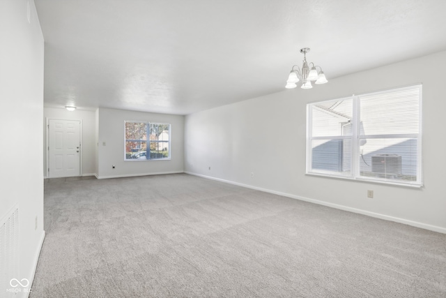 spare room with a notable chandelier and light colored carpet