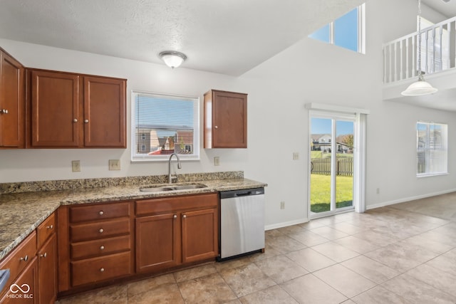 kitchen featuring light stone counters, a textured ceiling, sink, and stainless steel dishwasher