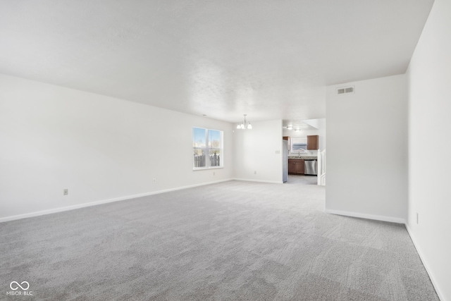 unfurnished living room with light carpet and an inviting chandelier