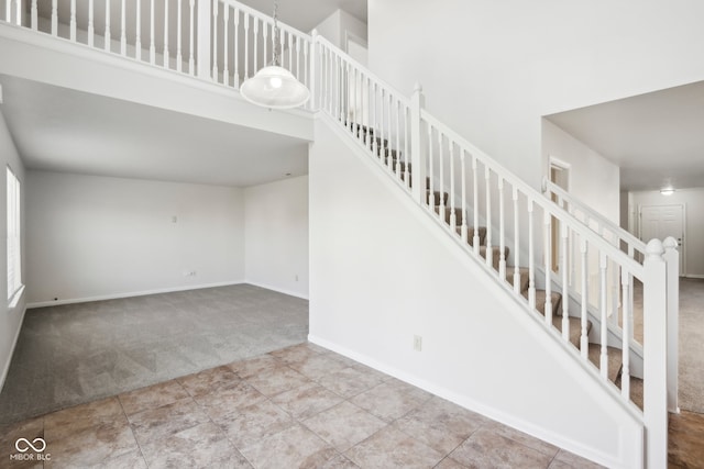 stairs with a high ceiling and carpet flooring