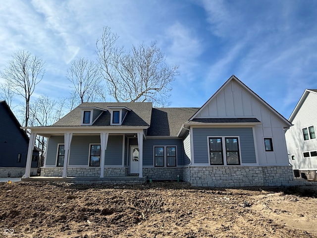 view of front facade featuring stone siding, covered porch, and board and batten siding