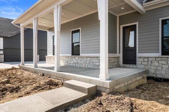 view of exterior entry with covered porch and stone siding