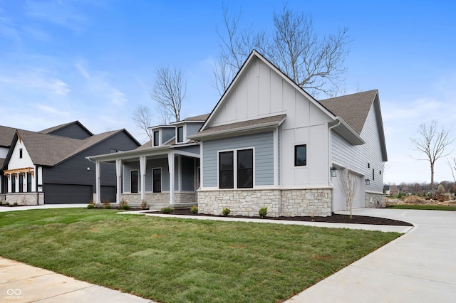 view of front of home with driveway, board and batten siding, stone siding, and a front yard