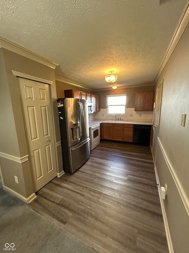 kitchen with dark wood-type flooring, crown molding, sink, appliances with stainless steel finishes, and a textured ceiling