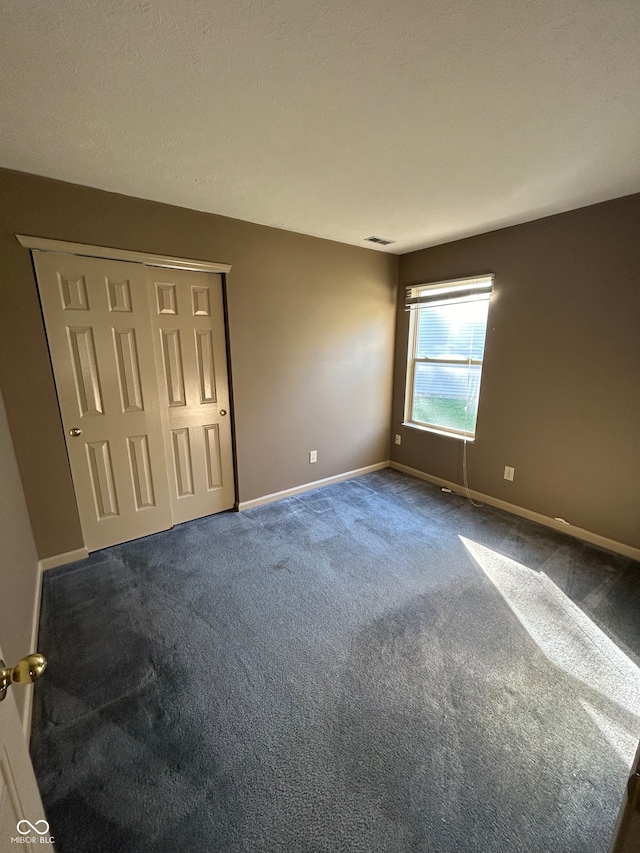 unfurnished bedroom featuring dark colored carpet and a closet