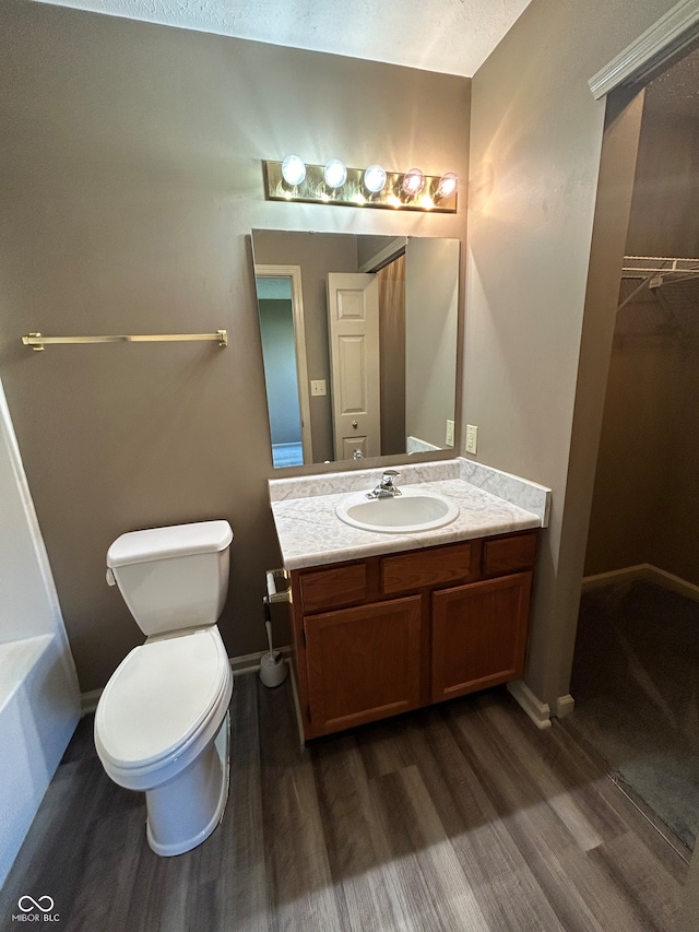 bathroom with toilet, a bathing tub, vanity, and wood-type flooring