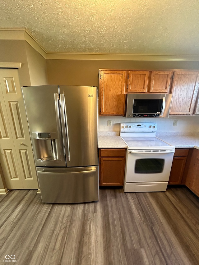 kitchen with appliances with stainless steel finishes, decorative backsplash, a textured ceiling, and dark hardwood / wood-style flooring