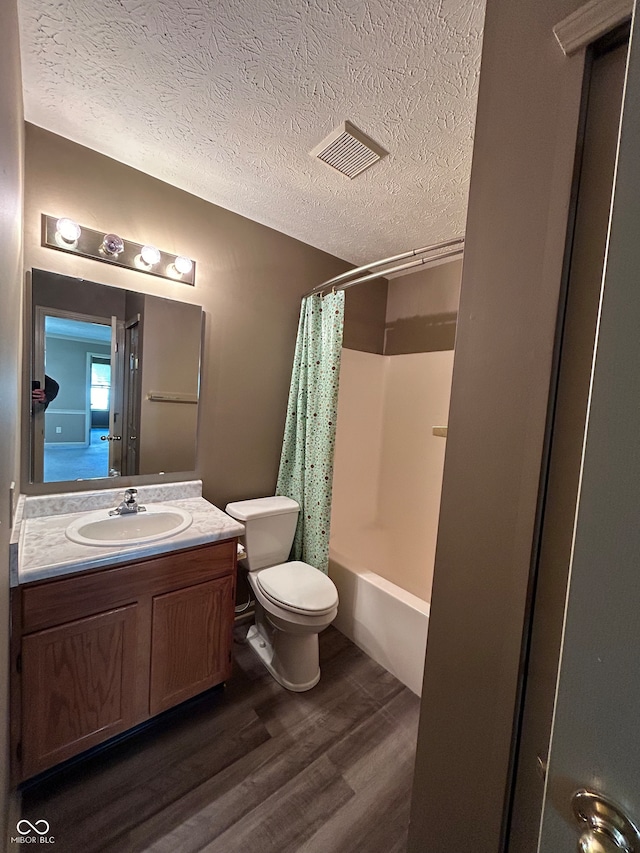 full bathroom featuring a textured ceiling, hardwood / wood-style flooring, toilet, vanity, and shower / tub combo with curtain