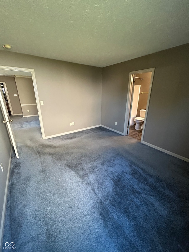 spare room featuring a textured ceiling and dark colored carpet