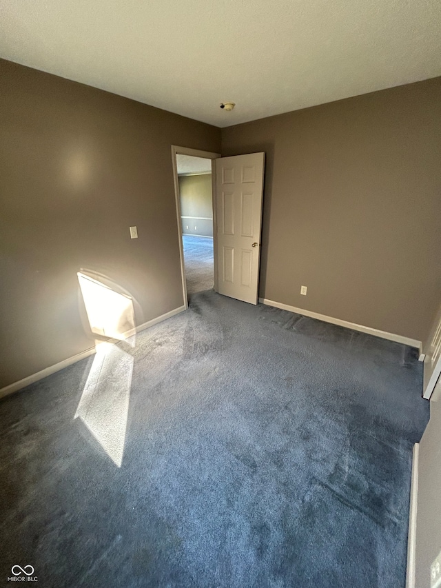 spare room with dark colored carpet