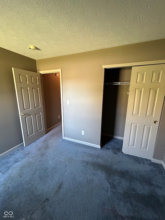 unfurnished bedroom with a closet, a textured ceiling, and dark carpet