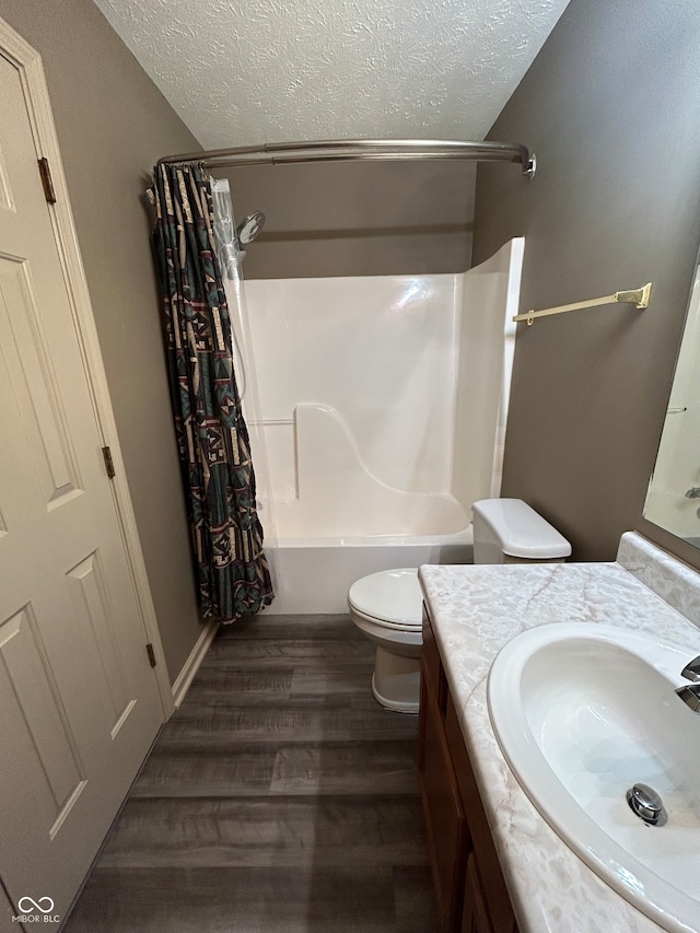 full bathroom with a textured ceiling, hardwood / wood-style floors, toilet, vanity, and shower / bathtub combination with curtain