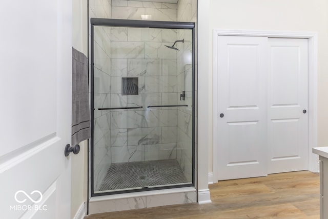 bathroom featuring vanity, wood-type flooring, and a shower with door