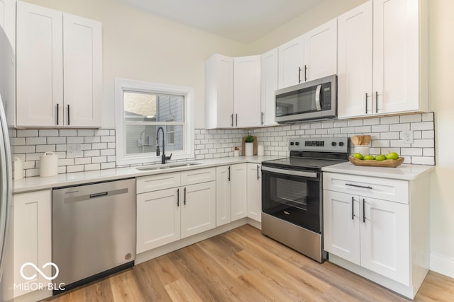 kitchen with light hardwood / wood-style floors, white cabinetry, sink, and appliances with stainless steel finishes