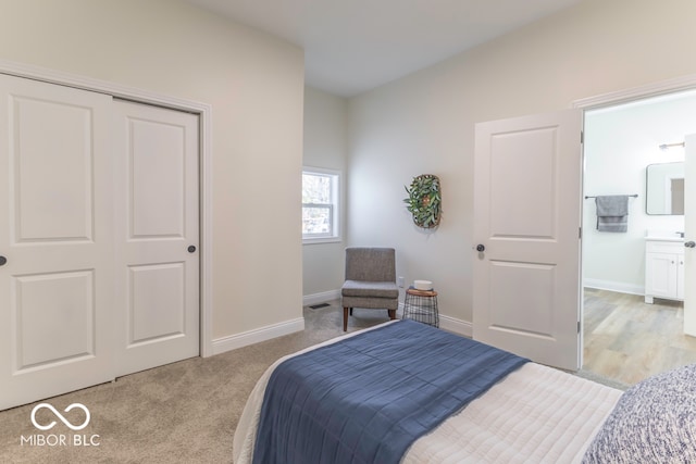 bedroom featuring a closet, light carpet, and ensuite bath