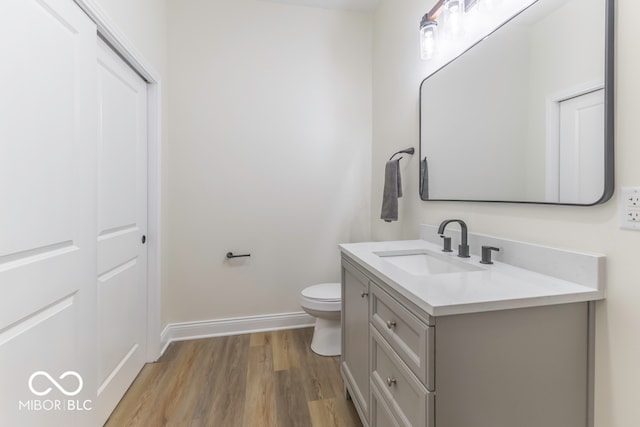 bathroom with toilet, vanity, and hardwood / wood-style flooring