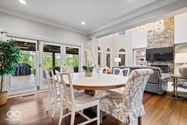 dining area featuring a chandelier, dark hardwood / wood-style floors, built in features, a fireplace, and crown molding