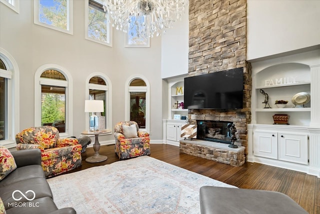 living room featuring a fireplace, dark hardwood / wood-style floors, a high ceiling, and built in features