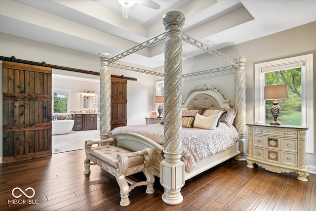 bedroom featuring a barn door, multiple windows, and hardwood / wood-style flooring