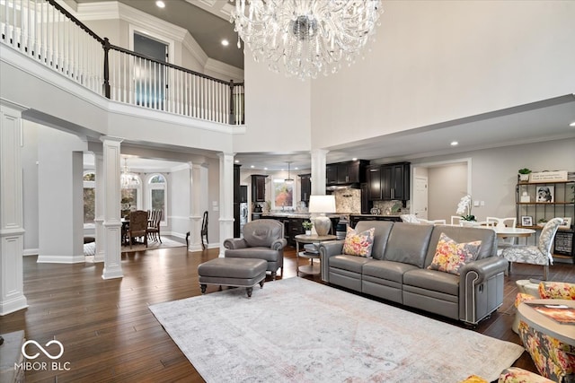 living room with a notable chandelier, ornamental molding, a high ceiling, and dark hardwood / wood-style floors