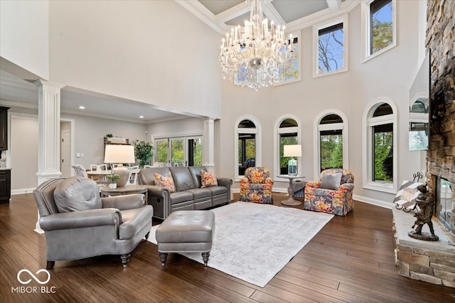 living room featuring dark wood-type flooring, ornate columns, a towering ceiling, and a chandelier