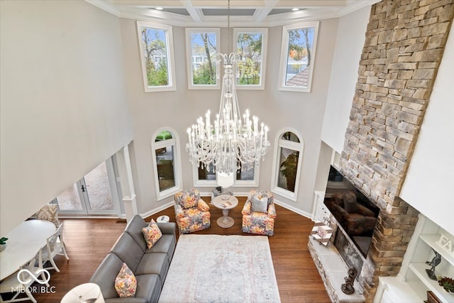 living room featuring dark hardwood / wood-style flooring, ornamental molding, a fireplace, a notable chandelier, and coffered ceiling