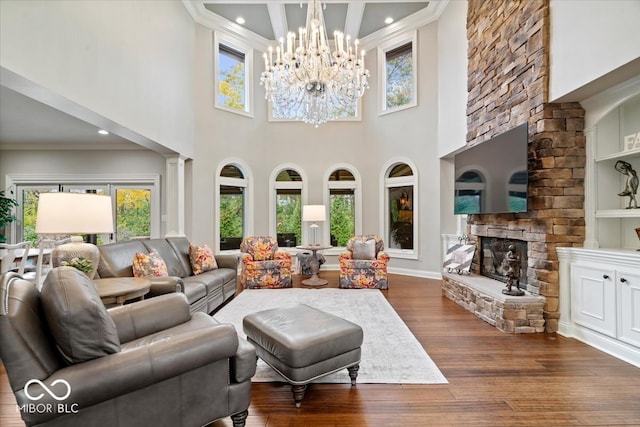 living room featuring a stone fireplace, ornate columns, a towering ceiling, and dark hardwood / wood-style flooring