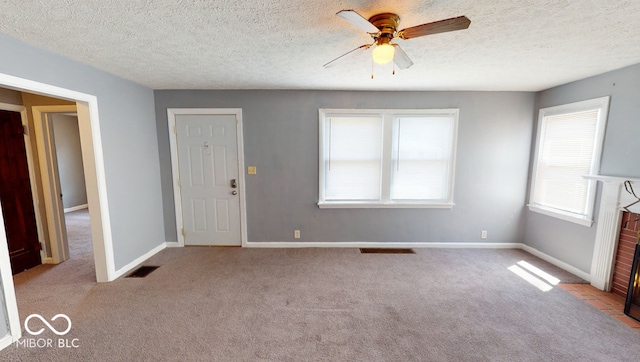 carpeted spare room featuring a textured ceiling, a brick fireplace, and ceiling fan