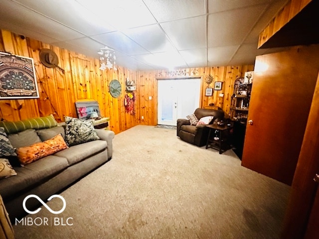 living room featuring a drop ceiling, carpet floors, and wood walls