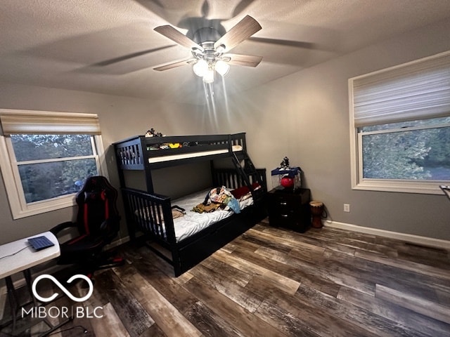 bedroom with dark wood-type flooring, ceiling fan, and a textured ceiling