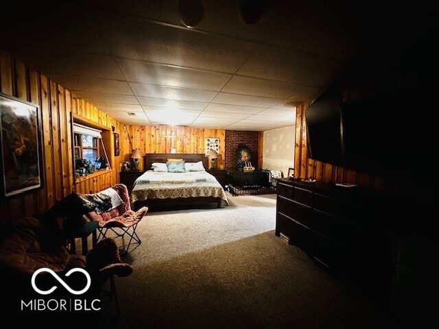 carpeted bedroom featuring a drop ceiling and wood walls