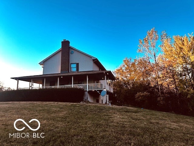 rear view of house featuring covered porch and a lawn