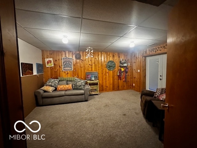 living room with carpet floors, wooden walls, and a paneled ceiling