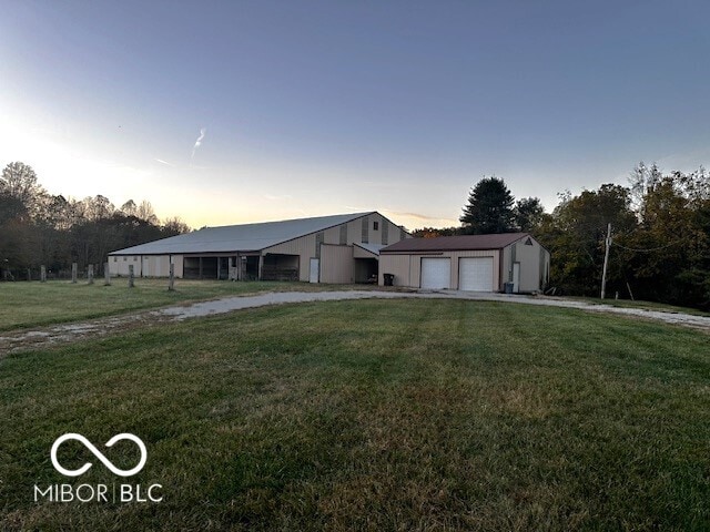 view of front of property with a garage, an outdoor structure, and a lawn