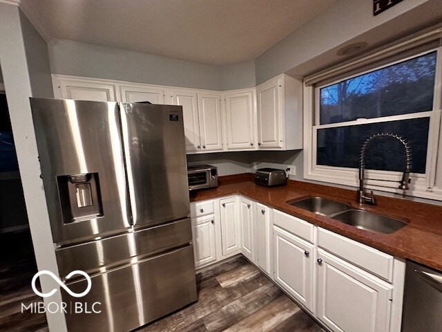 kitchen featuring dark hardwood / wood-style floors, white cabinetry, sink, dishwashing machine, and stainless steel refrigerator with ice dispenser