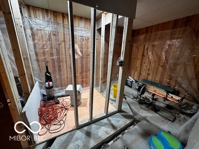 miscellaneous room featuring a drop ceiling and wooden walls