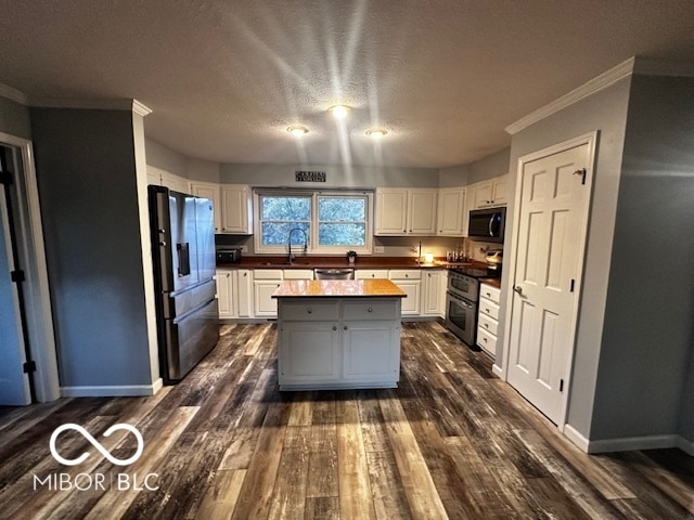 kitchen with white cabinetry, appliances with stainless steel finishes, a center island, and dark wood-type flooring