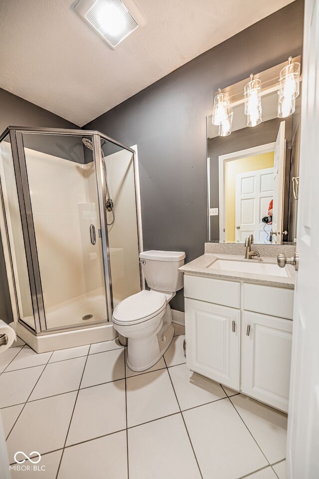 bathroom featuring toilet, vanity, tile patterned floors, and a shower with shower door