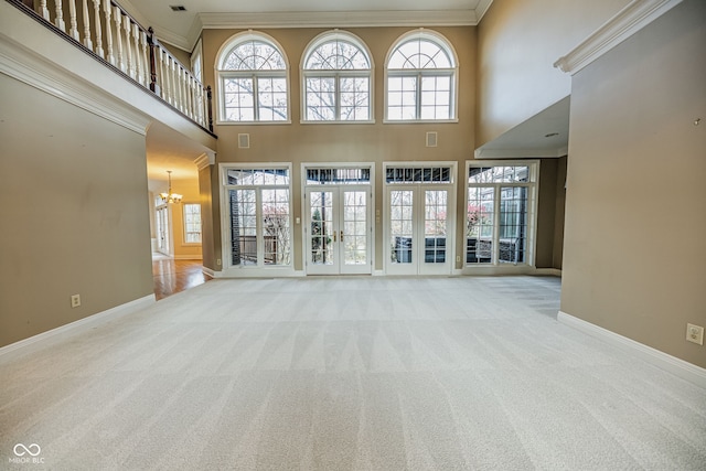 unfurnished living room with french doors, a towering ceiling, light carpet, a chandelier, and ornamental molding