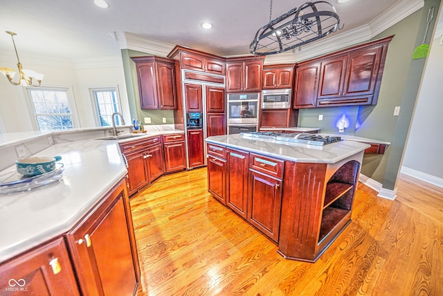 kitchen featuring a kitchen island, built in appliances, pendant lighting, a chandelier, and light hardwood / wood-style flooring