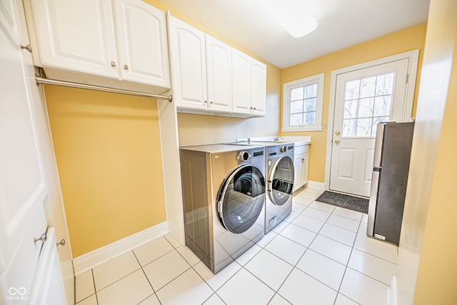 clothes washing area featuring cabinets, light tile patterned flooring, and independent washer and dryer