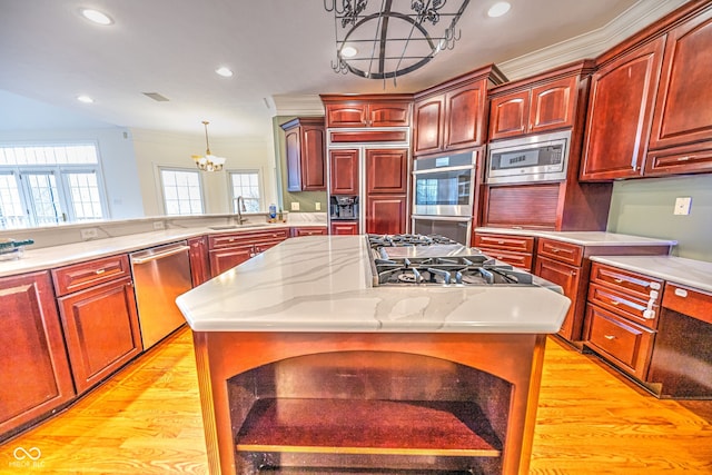 kitchen featuring a center island, built in appliances, a chandelier, pendant lighting, and light wood-type flooring