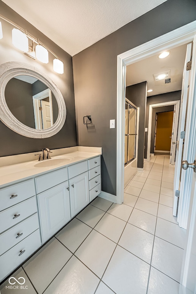 bathroom featuring vanity, tile patterned floors, an enclosed shower, and a textured ceiling