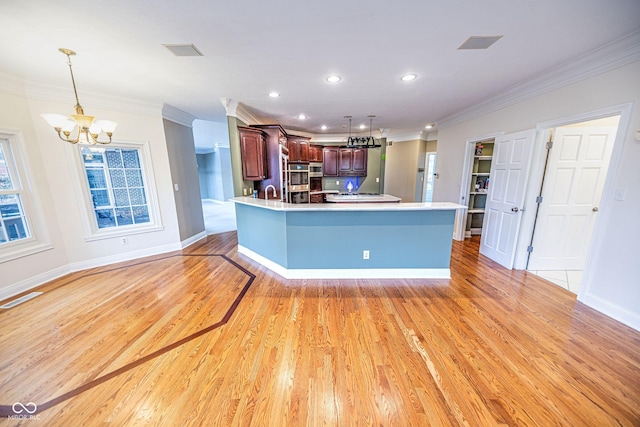 808 Copperfield Xing, Danville, IN 46122 - kitchen with a chandelier, ornamental molding, light wood-style floors, light countertops, and a peninsula