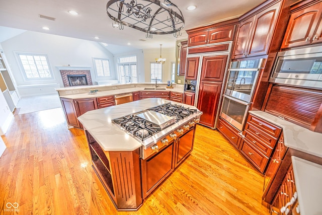808 Copperfield Xing, Danville, IN 46122 - kitchen featuring a chandelier, built in appliances, a peninsula, a sink, and lofted ceiling